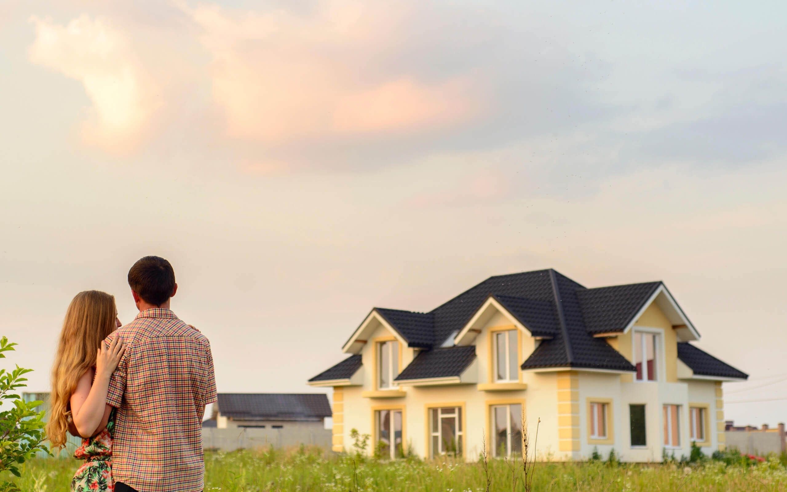 A couple standing in front of their dream home.